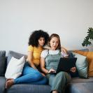 Lesbian couple sitting on couch looking at laptop