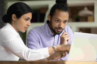 Two people working at a laptop