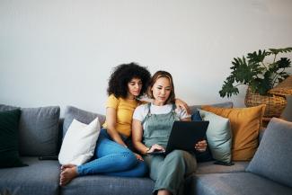 Lesbian couple sitting on couch looking at laptop