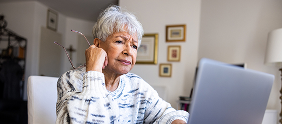 A senior woman with a concerned emotion at her laptop computer