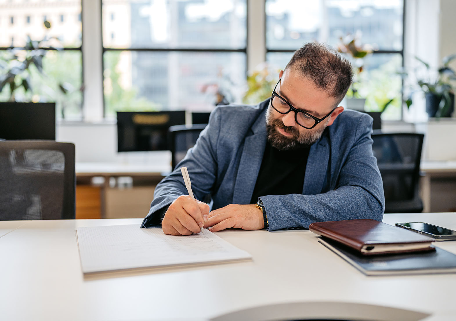 Mid Adult Man Writing In A Notebook At The Desk In The Office Building In Sydney In Australia