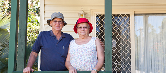 Happy Healthy Seniors Couple on porch in front of house